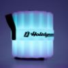 Plastic bluetooth speaker labeled with Holidynamics logo on the middle band displayed lit teal and right facing on white background