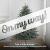 7.5' Full Fraser Pine displayed in lifestyle shot of living room, lit multi-color, graphic banner across the image with text saying "On my way!". Caption under banner says "Just a little longer! This item is on the way and expected to land by late summer 2025."