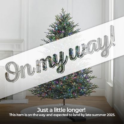 7.5' Full Fraser Pine displayed in lifestyle shot of living room, lit multi-color, graphic banner across the image with text saying "On my way!". Caption under banner says "Just a little longer! This item is on the way and expected to land by late summer 2025."