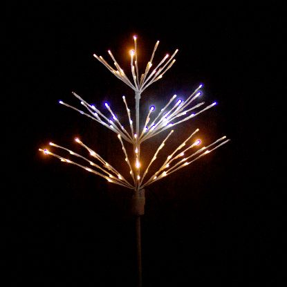 Paramount Spritzer yard stake decoration illuminated in champagne, warm white and pure white, against a black background.