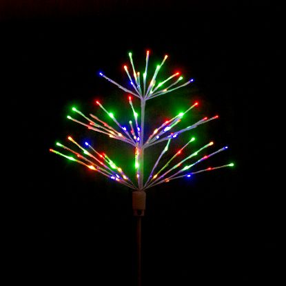 Paramount Spritzer yard stake decoration illuminated in multicolored rainbow against a black background.